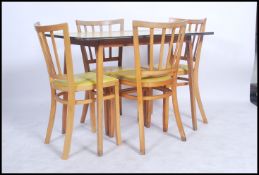 A 1950's formica topped kitchen table in yellow with four matching beech wood chairs, seat pads