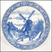 A 20th century Delft ceramic wall hanging charger plate having a central tondo depicting a