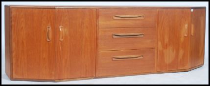 A 1970's retro G-Plan teak wood sideboard of angular form comprising angled end cupboards with a