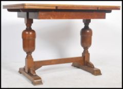 A 1930's oak draw leaf refectory dining table raised on turned legs united by stretcher having
