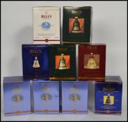 A group of 9 Bells Whiskey commemorative bell shaped ceramic decanters all unused most in original