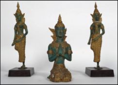 A trio of Thai cold painted and gilded bronze statues of deity bodhisattva. Two being raised on