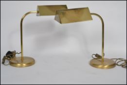 A pair of vintage style 20th century brass bankers lamps raised on circular bases with arched