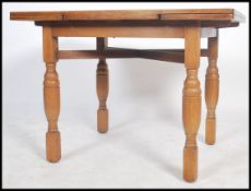 A 1930's oak draw leaf refectory dining table raised on turned legs having fitted frieze with