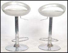 A pair of 20th century chrome and silvered bar stools being raised on chrome terraced bases, gas