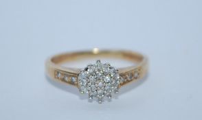 A hallmarked 9ct gold and diamond cluster ring with diamond accent shoulders. Diamonds approx 20pts.