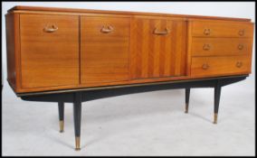 A 1950's retro teak wood sideboard of stunning angular form being raised on an ebonised x-frame base