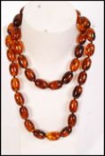 A vintage early 20th century single row, graduated, olive-shaped amberite bead necklace, strung on