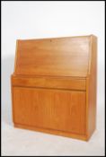 A 1970's teak wood bureau having a drop down door with fitted interior above a cupboard and twin