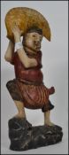 An unusual 20th century Oriental carving of a man holding a giant golden fish above his head