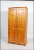 A contemporary antique style pine double wardrobe having plinth base with bun feet, two full