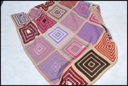 A large 20th century retro crochet granny square blanket / bed throw being multicoloured in a