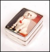 A silver rectangular pill box with a hinged enamel