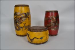 A set of 3 Chinese drums of variant sizes having animal skin to top and bottom and studded, being