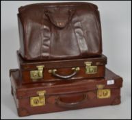 A good group of vintage leather / hide luggage to include two suit cases / attache cases and a pig