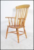 A Victorian style beech and elm wood windsor armchair having turned legs, saddle seat with shaped