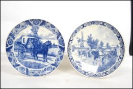Two 20th century Delft ceramic wall hanging charger plates each having a central tondo depicting