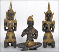 A trio of cold painted ebonised and gilded hindu deity's, 2 in the lotus position, one with