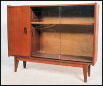 A vintage 1970's teak wood bookcase cabinet raised on tapered legs with a glass sliding door.
