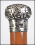 A continental hallmarked silver topped malacca walking stick / cane, with scroll work detail to
