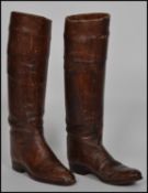 A pair of vintage early to mid 20th century brown / tan leather riding boots retaining within wooden