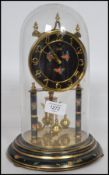 A 20th century anniversary clock complete in the glass dome with brass swing weights having black