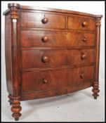 A Victorian large bow front flame mahogany chest of drawers raised on turned legs with columns to