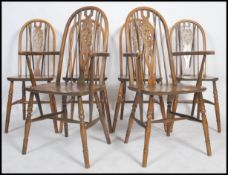 A set of 4 20th century wheelback dining chairs raised on turned legs united by stretchers over