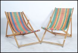 A pair of 1970's retro wooden folding deck chairs having striped canvas material to create the