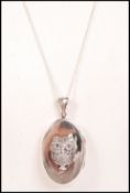 A silver locket and necklace combination. The oval