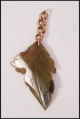 A 9ct gold and jade leaf pendant. The carved green
