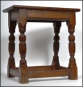 A 17th century style country oak peg jointed stool raised on gun barrel turned legs united by square
