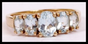 A 9ct gold ladies  5 stone dress ring. The 5 gradu