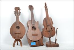 A collection of three carved miniature musical wind - up instruments to include a Violin with bow,