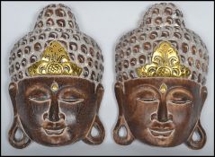A pair of Indonesian carved wooden decorative wall display masks of deities having applied gilt