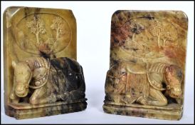 A pair of Chinese carved soapstone bookends, each bookend depicting a horse with Chinese scenes