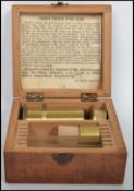 A vintage early 20th century brass miniature microscope complete in a fitted wooden case with a