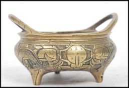 A Chinese bronze tripod censor with twin loop handles, of bellied oval form having dragons to the