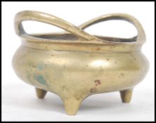A Chinese bronze tripod censor with twin loop handles, of bellied oval form,the underside bearing