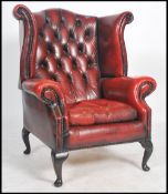 A stunning Queen Anne style oxblood leather chesterfield armchair having scroll arms and cabriole