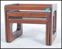 A set of three retro Danish inspired teak wood nest of tables raised on block supports with drop