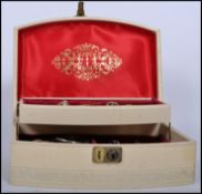 A vintage cream and gilt jewellery box with lock to front opening to reveal a collection of