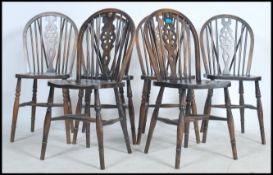 A set of 6  20th century wheelback dark oak dining chairs raised on turned legs with saddle seats