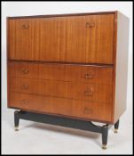A 1970's teak G-plan librenza bureau chest of drawers being raised on an ebonized suspension set