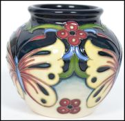 A Moorcroft tube lined squat vase decorated in the Burley Butterfly vase having a waisted neck