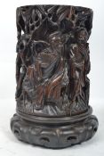 A 19th century Oriental hardwood brush pot heavily carved with scholars and musicians in a garden