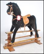 A vintage child's rocking horse of larger proportions raised on a wooden rocker with leather saddle,
