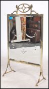 An art nouveau brass fire screen having a pierced gallery top with cut mirror panels having