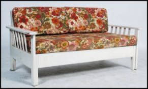 A vintage 1960's painted metamorphic day bed, slated back open arms with original seat covers.