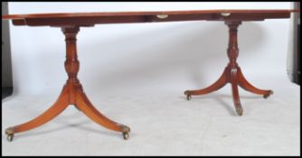 A good quality mahogany ebony inlaid Regency revival twin pedestal dining table being raised on